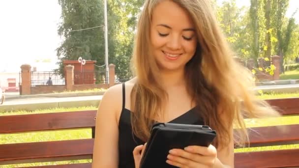 Una joven en un parque con una tableta. Verano — Vídeos de Stock