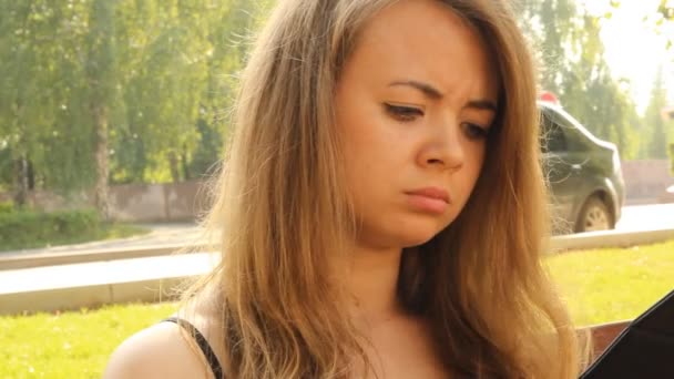 Una joven en un parque con una tableta. Verano — Vídeos de Stock