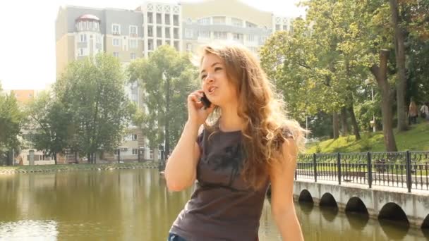 Joven mujer de pelo largo hablando en un teléfono móvil — Vídeos de Stock