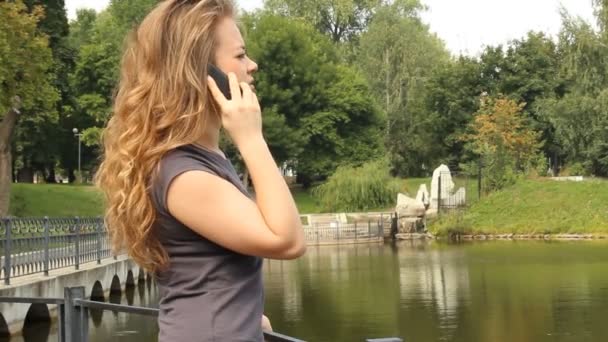 Jonge langharige vrouw praten op een mobiele telefoon — Stockvideo