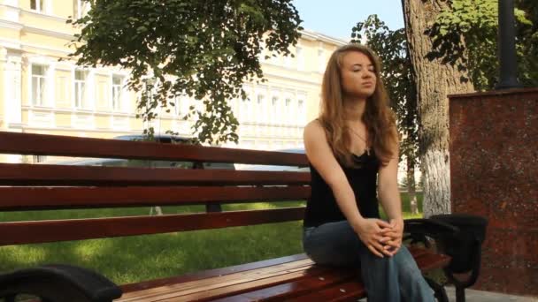 在公园的长凳上的年轻女孩。等待夏天 — 图库视频影像