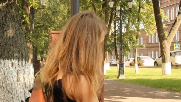 Chica joven leyendo una revista brillante en el parque — Vídeo de stock