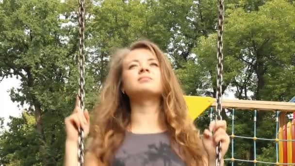 Young girl swinging on a swing in the park — Stock Video