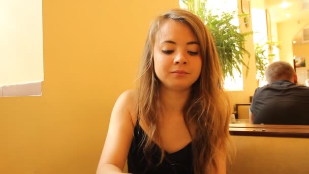 Una giovane ragazza in una tavola calda (ristorante, caffè ) — Video Stock