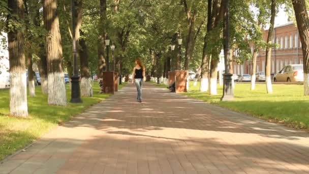Een jong meisje in een park. lopen vaststelling van de avenue — Stockvideo