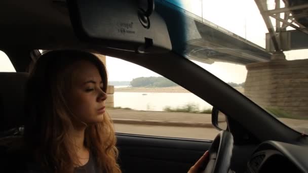 Menina de cabelos compridos ao volante de um carro. Embankment fluvial — Vídeo de Stock