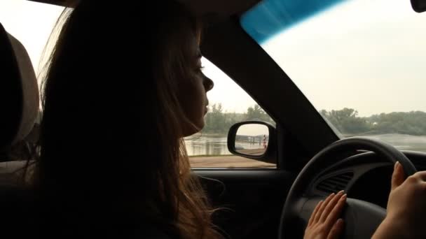 Chica de pelo largo al volante de un coche. Arrastramiento del río — Vídeo de stock