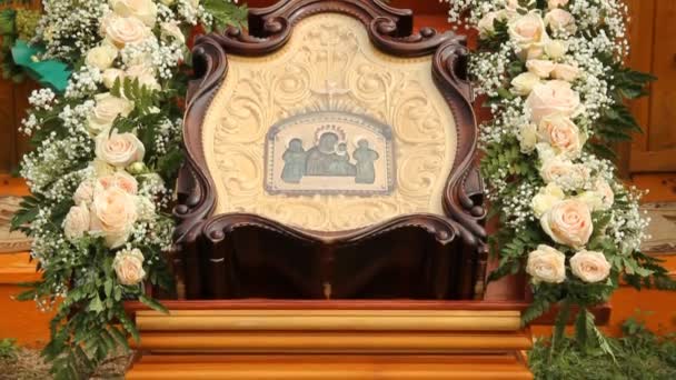 Ancient icon in a wooden frame surrounded by flowers — Stock Video