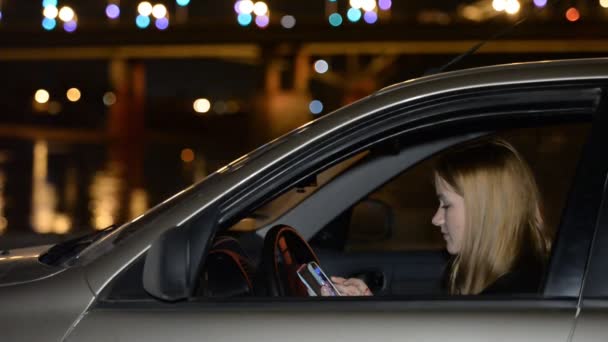 Молодая девушка в машине на ночной набережной. Встреча, ожидание, любовь, свидания — стоковое видео