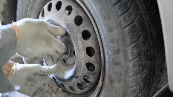 Car mechanic screwing wheel to car