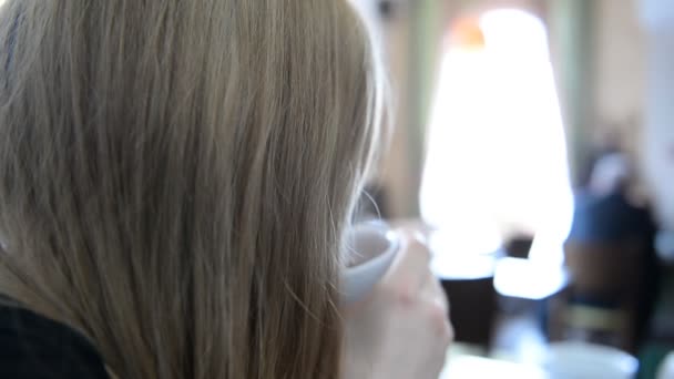 Ung attraktiv kvinna dricker kaffe i caféet — Stockvideo