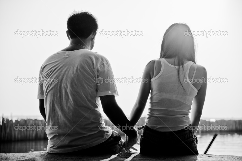 Couple sit on sunset beach