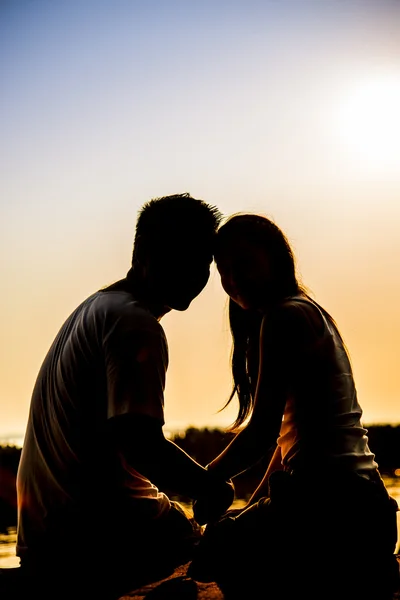 Casal encantador sentar-se no pôr do sol com cena silhueta — Fotografia de Stock