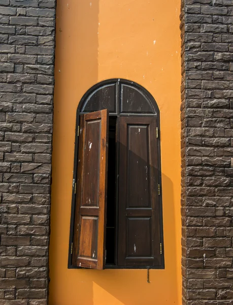 Holzfenster an orangefarbener Wand — Stockfoto