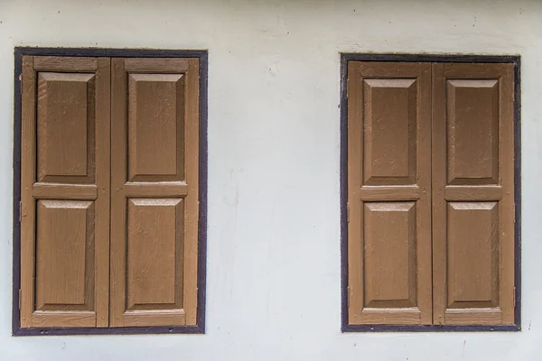Dvě hnědá dřevěná okna na bílé zdi — Stock fotografie
