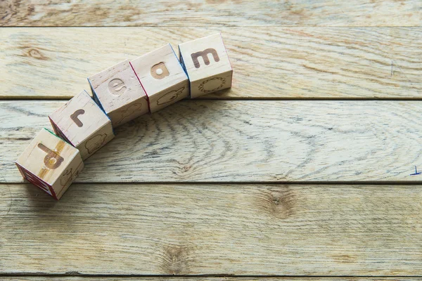 Wooden block word is dream on wooden background — Stock Photo, Image