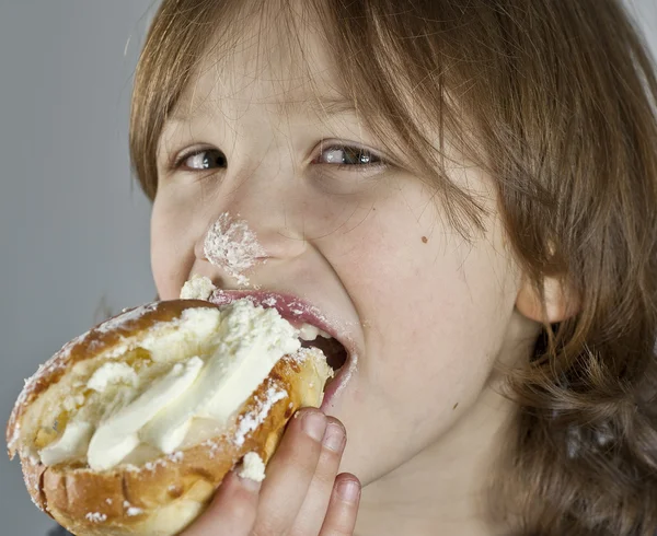 Junge genießt ein Cremebrötchen mit Mandelpaste — Stockfoto