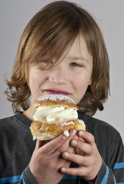 Niño con un bollo de crema con pasta de almendras —  Fotos de Stock