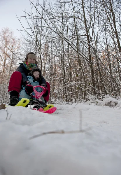 Matka a dítě jede z kopce na sněhu saně — Stock fotografie
