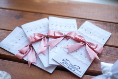 Ahşap masadaki kurdeleli düğün davetiyeleri. 