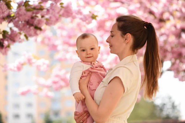 Annem bahar parkında bebeği kollarında tutuyor. 
