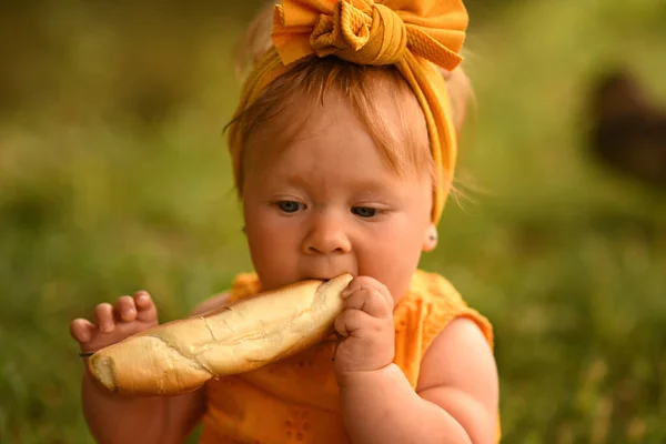 公園の少女がアヒルに餌をやる 子供はアヒルと遊ぶ 黄色のドレスの女の子はパンを食べる — ストック写真