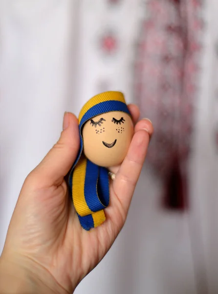 Yüzü boyalı yumurta, Ukrayna kurdelesi ve arka planda Ukrayna süsü. Paskalya arkaplanı.