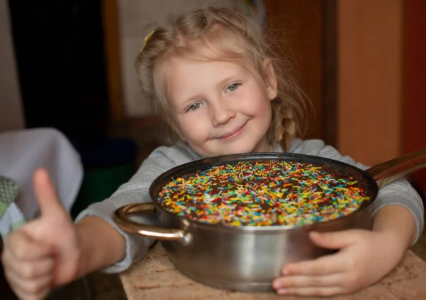 Elinde paskalya pastası olan anaokulu kızı sınıfı parmağıyla gösteriyor. Yiyeceği olan küçük çocuk..