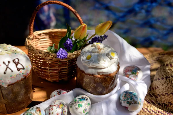 Paskalya pastaları, yumurtalar ve Paskalya gününde sarı laleler ve mor çiçeklerle dolu ahşap sepet..