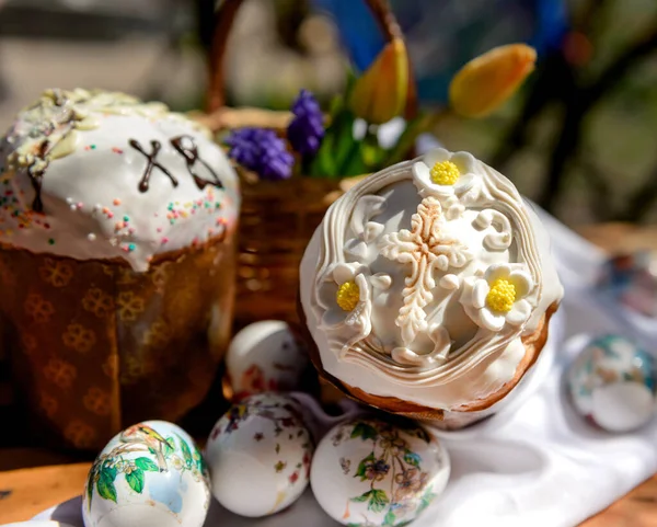 Paskalya pastaları, yumurtalar ve Paskalya gününde sarı laleler ve mor çiçeklerle dolu ahşap sepet..