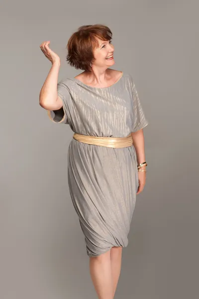 Beautiful fashionable mature woman in grey dress. Studio shot. — Stock Photo, Image