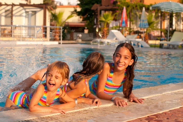 Tres niñas jugando y chapoteando en la piscina Imágenes de stock libres de derechos