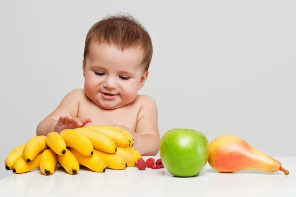 Happy baby med frukter Royaltyfria Stockbilder