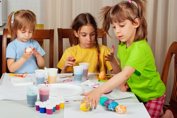 Drie kleine meisjes (zusters) schilderen op Pasen eieren — Stockfoto