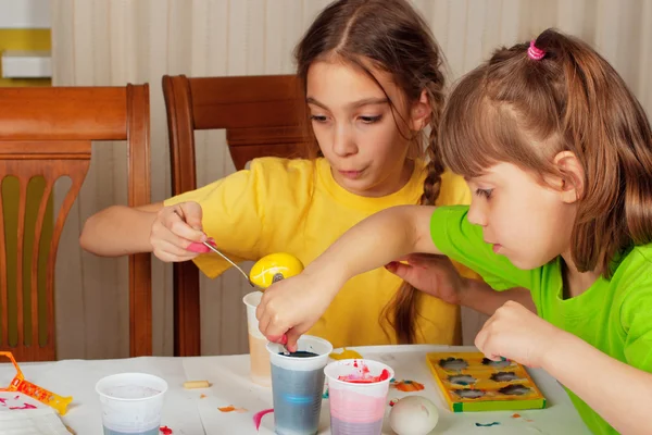 Twee kleine meisjes (zusters) schilderen op Pasen eieren — Stockfoto