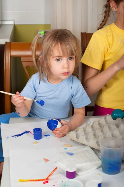 Two little girls (sisters) painting on Easter eggs Stock Photo