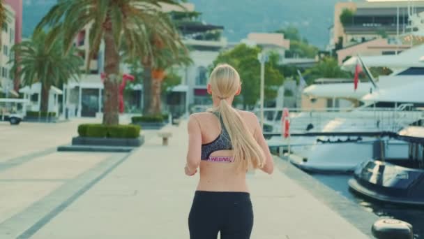 Back view of fit girl with long blonde hair jogging — Stock videók