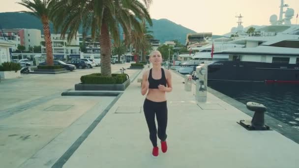 Happy fit žena ve sportovním obleku jogging a usmívá se na nábřeží — Stock video