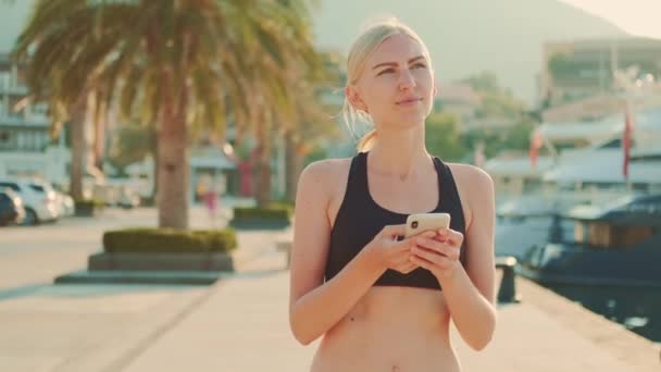 Attractive fitness woman chatting on smartphone during sport break outdoor — Stock videók