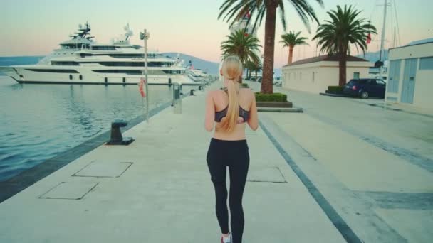 Back view of blonde sport woman jogging in port — Wideo stockowe