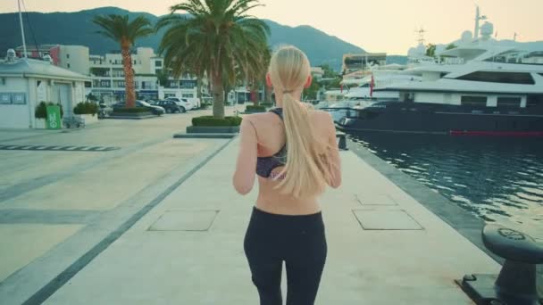 Back view of blonde sport woman jogging in port — Wideo stockowe
