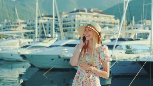 Elegantní žena mluví na smartphone na ulici s jachtami v pozadí — Stock video