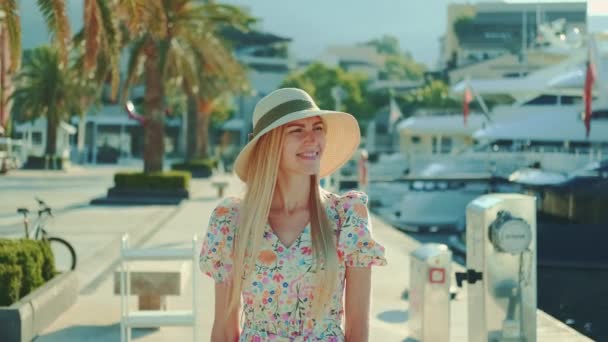 Gelukkig jong vrouw in mooie outfit wandelen in de haven en glimlachen — Stockvideo