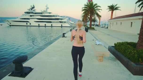 Back view of blonde sport woman jogging in port — Stock videók