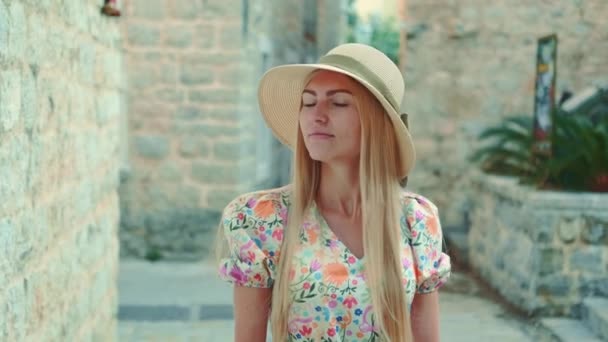 Elegant woman in summer hat walking down the old street — стоковое видео
