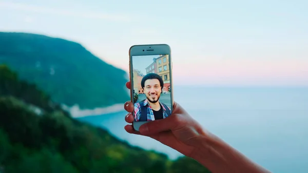 Gros plan du smartphone tenu par la main lors d'un appel vidéo avec un homme devant la mer — Photo