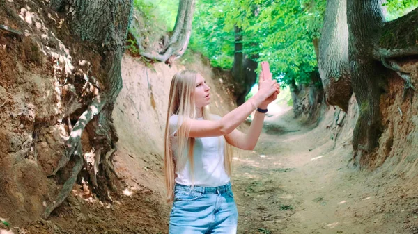 Blonde young woman making photos on smartphone in magical Roots Gorge — Stock Photo, Image