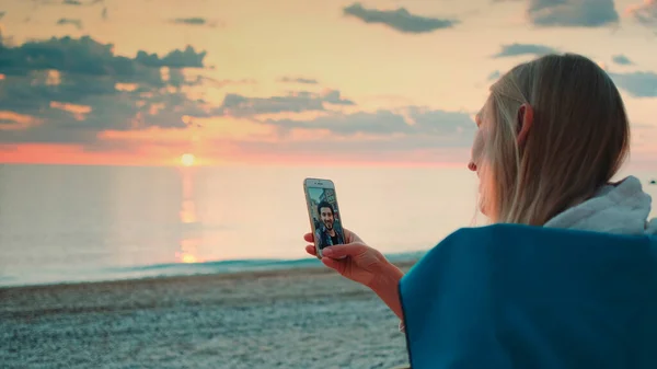 Jeune femme faisant appel vidéo à son ami avec smartphone sur la plage — Photo