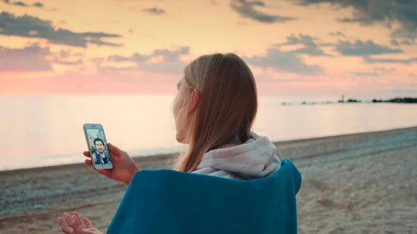 Femme faisant appel vidéo avec smartphone sur le bord de la mer — Photo