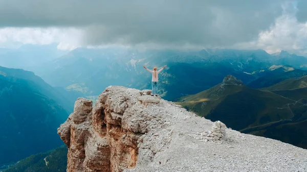 Потрясающий пейзаж горных скал и женщины, стоящие на вершине с протянутыми руками — стоковое фото